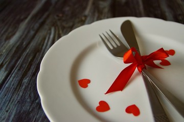 White plate with cutlery tied with red ribbon for romantic meeting