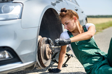 Woman in uniform working for car brake maintenance. Car repair. Safety work.