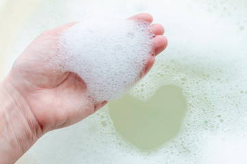 Fototapeta premium soap suds on a person's hand on a background of soap suds. The concept of cleanliness and hygiene.