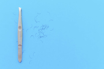 tweezers for plucking eyebrows and hair on a blue background with a place for writing