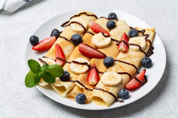 Pancakes with blueberry, strawberry, banana and chocolate sauce for breakfast. Delicious homemade pancakes. 