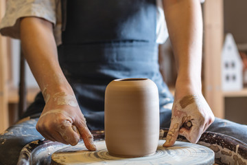 Woman potter working on a Potter's wheel making a vase. Master pulls the jug off the circle gently holding it in hands