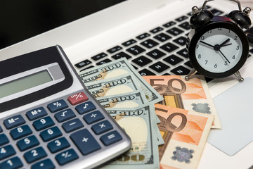 Business concept - laptop money dollars and euro with clock.