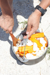 Tourist cooking meat with vegetables in a cauldron on the beach.