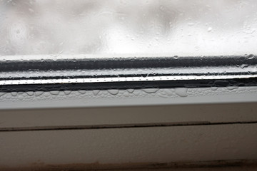 High humidity in the form of condensation on a transparent glass with large drops of natural water. Defective plastic window with condensation