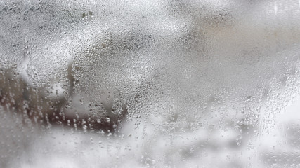 Transparent condensate in the foggy background, water dripping on clear glass. Drops of condensation close-up macro. Steam on the glass. Condenser.