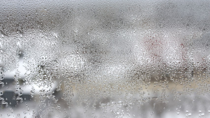 High humidity in the form of condensation on a transparent glass with large drops of natural water. Defective plastic window with condensation