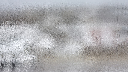 Transparent condensate in the foggy background, water dripping on clear glass. Drops of condensation close-up macro. Steam on the glass. Condenser.