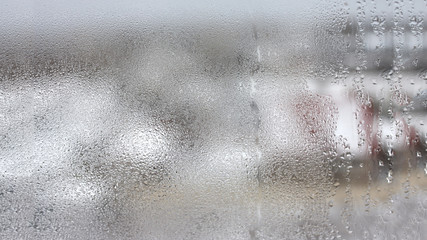 High humidity in the form of condensation on a transparent glass with large drops of natural water. Defective plastic window with condensation