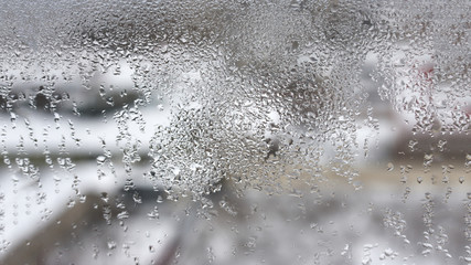High humidity in the form of condensation on a transparent glass with large drops of natural water. Defective plastic window with condensation