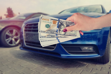 salesman selling auto in car shop or businessman buying new car holding dollar in hand