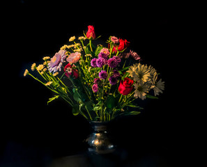 Multicolored Flower Arrangement in Black Clay Vase Against Black Background