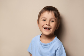 Portrait of cute little boy on beige background