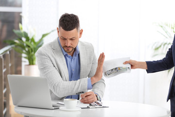 Businessman refusing to take bribe at table indoors