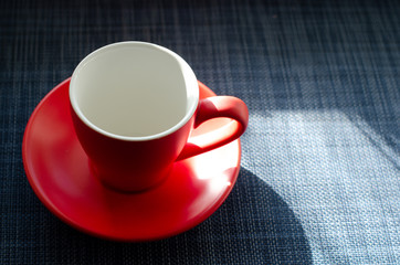  Empty red coffee cup on saucer on blue texture stand in daylight