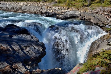 Wild waterfall on Siffleur river, beautiful blue clear water with rocky bank, forest on the...