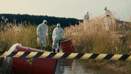 Group of scientists exploring polluted landscape at reed swamp analyzing ecology condition on sunny...