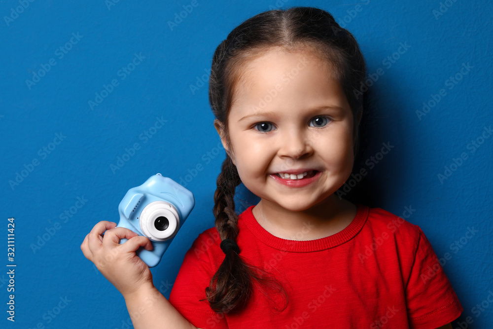 Poster Little photographer with toy camera on blue background