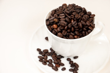 Coffee beans in a white glass with saucer on a white background