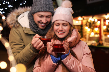 Happy couple with mulled wine at winter fair
