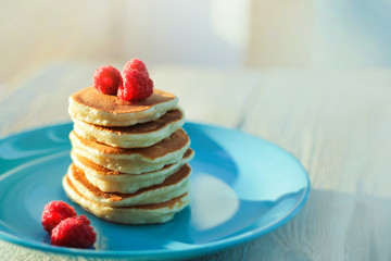 a stack of freshly baked pancakes decorated with raspberries. copcept delicious breakfast