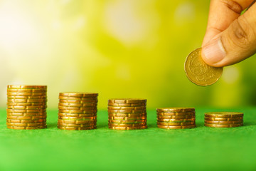 hand put coins on stacked money. growing saving money. money stack step up with blurry coins in bottle against blurry nature background. financial business investment concept. free copy space 