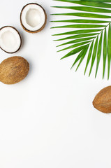 Tropical leaves and fresh coconut on light gray background top view copy space. Summer Flat lay background. Healthy cooking. Creative healthy food concept, half of coconut, nature