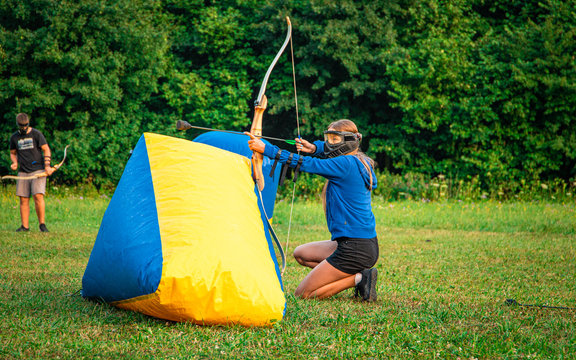 Girl kneeling behind an inflatable protection in order to get a good position to shoot her arrow