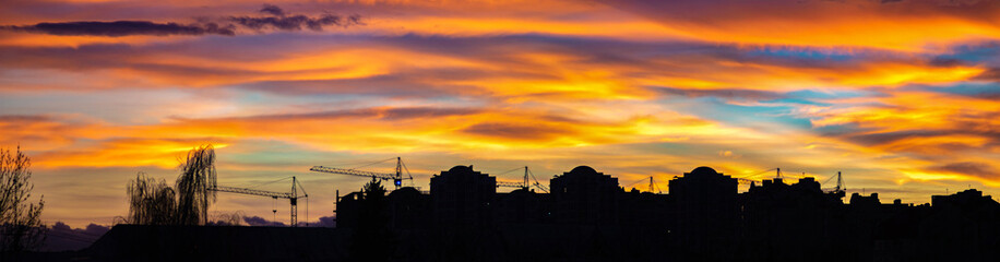 Panorama of colorful sunset sky over the silhouettes of houses