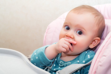 Feeding cute baby girl in pram with spoon