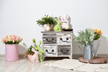 Rustic-style kids room with Easter decorations against a white wall, with wooden furniture and toys and flowers.