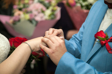 The bride and groom on their wedding day exchange wedding rings.