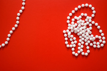 White beads on a red background, toned photo. Copy space, flat lay.
