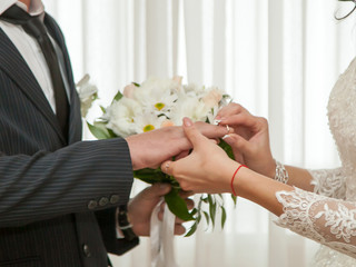 The bride and groom on their wedding day exchange wedding rings.