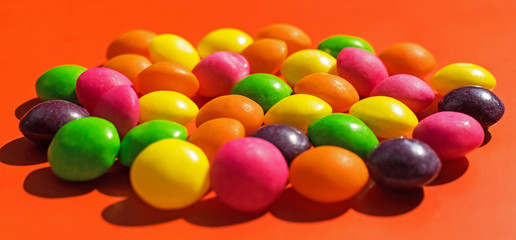 candy round, confection,  like balls in different colors. Many colorful candies on a red background.