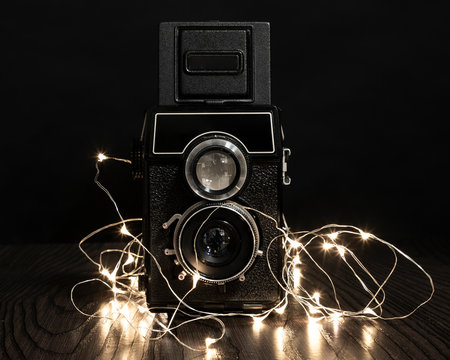 camara de fotos antigua rodeada de lucecitas en fondo negro