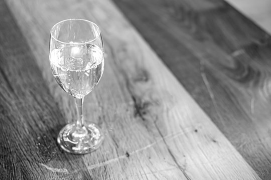 Featurebild Fasten oder Diät: Glas mit Wasser auf einem rustikalen, alten Holztisch - selektiver Fokus, schwarz und weiß, sehr viel Copyspace