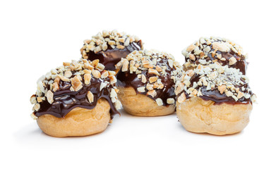 Homemade profiteroles covered with chocolate and chopped nuts isolated on white