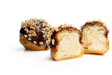Homemade profiteroles covered with chocolate and chopped nuts isolated on white