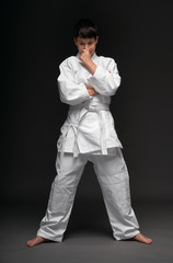 Fototapeta na wymiar a teenager dressed in martial arts clothing poses on a dark gray background, a sports concept