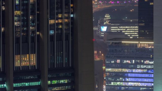Dubai International Financial Centre district with illuminated modern skyscrapers night timelapse. Aerial view from Downtown with traffic on streets and blinking windows on tower