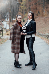 People, friends, teens and friendship concept - happy smiling pretty teenage girls hugging outdoors. Girlfriend friendship togetherness happiness smiling concept.  Girl posing with a panda toy