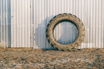 A huge wheel from a tractor against a metal fence. Industrial minimalism with a tire