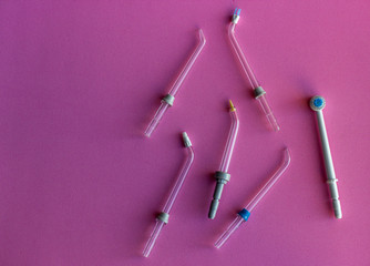Hangeable tips for oral irrigator on a pink background. A set of removable attachments for oral...