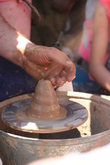 hands of potter creating a jar on circle
