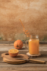 glass of fresh orange juice and oranges on cutting board