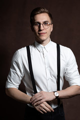 Man in round glasses, suspenders and a white shirt.