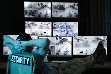 Security guard monitoring modern CCTV cameras at night