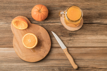 glass of fresh orange juice and oranges on cutting board