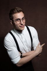 Man in round glasses, suspenders and a white shirt.